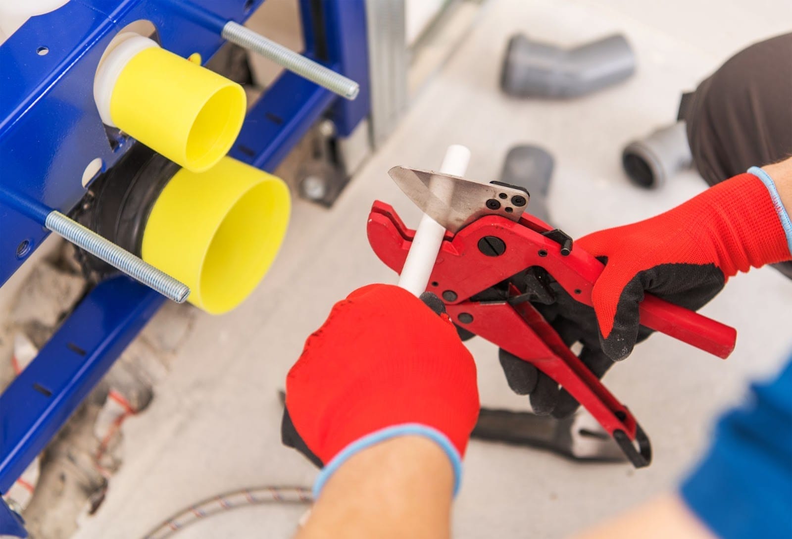Professional at work: a skilled worker cuts a pvc pipe with a specialized cutting tool while installing plumbing.