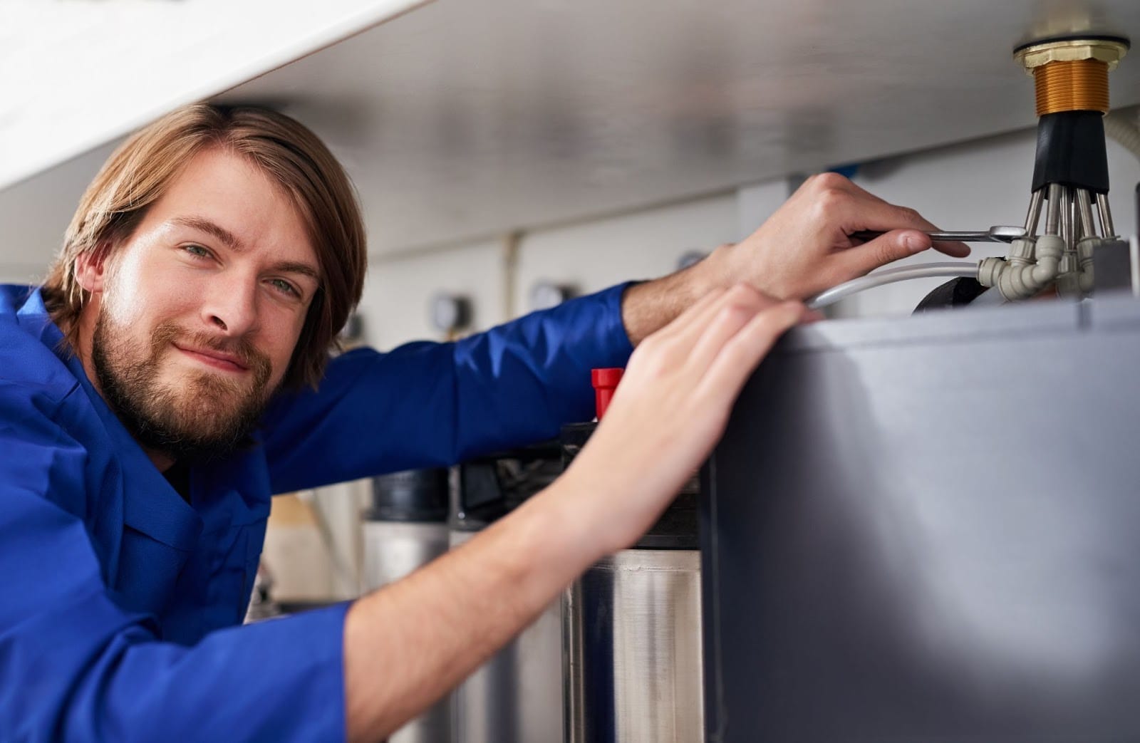 Professional technician smiling while servicing a home heating system.