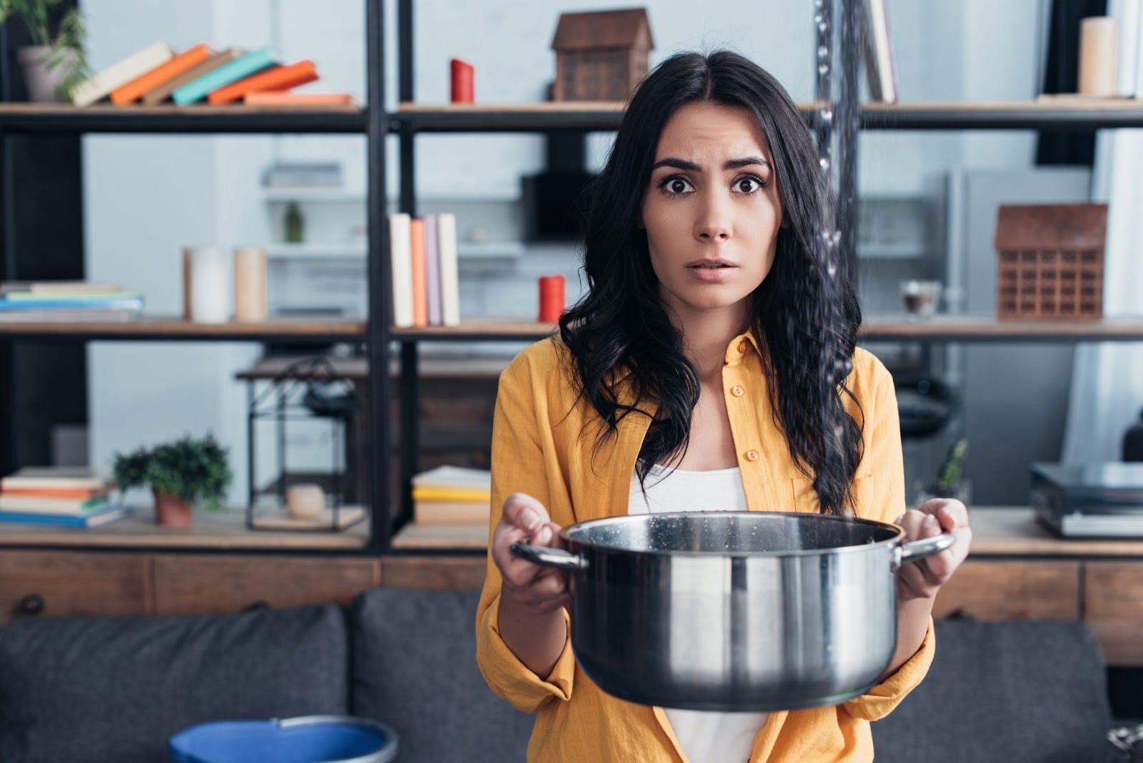 Perplexed woman holding a pot with a burnt meal, facing a cooking catastrophe.