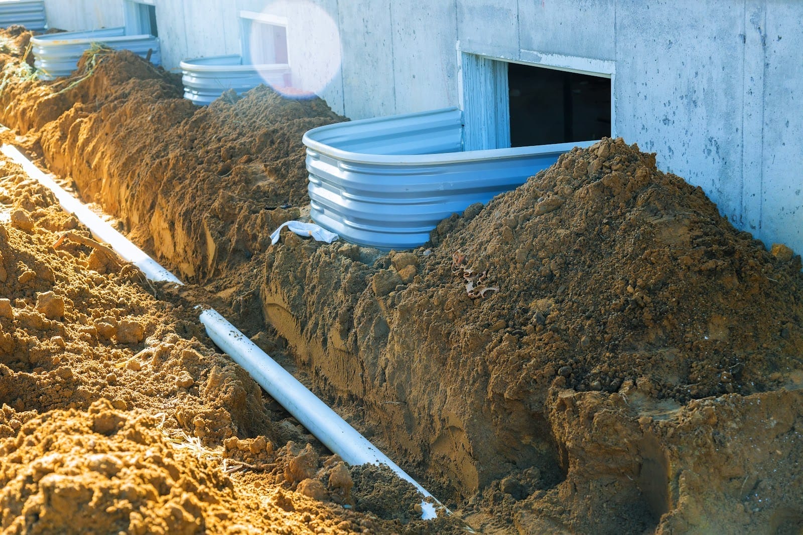 A trench filled with dirt and pipes in front of a house.