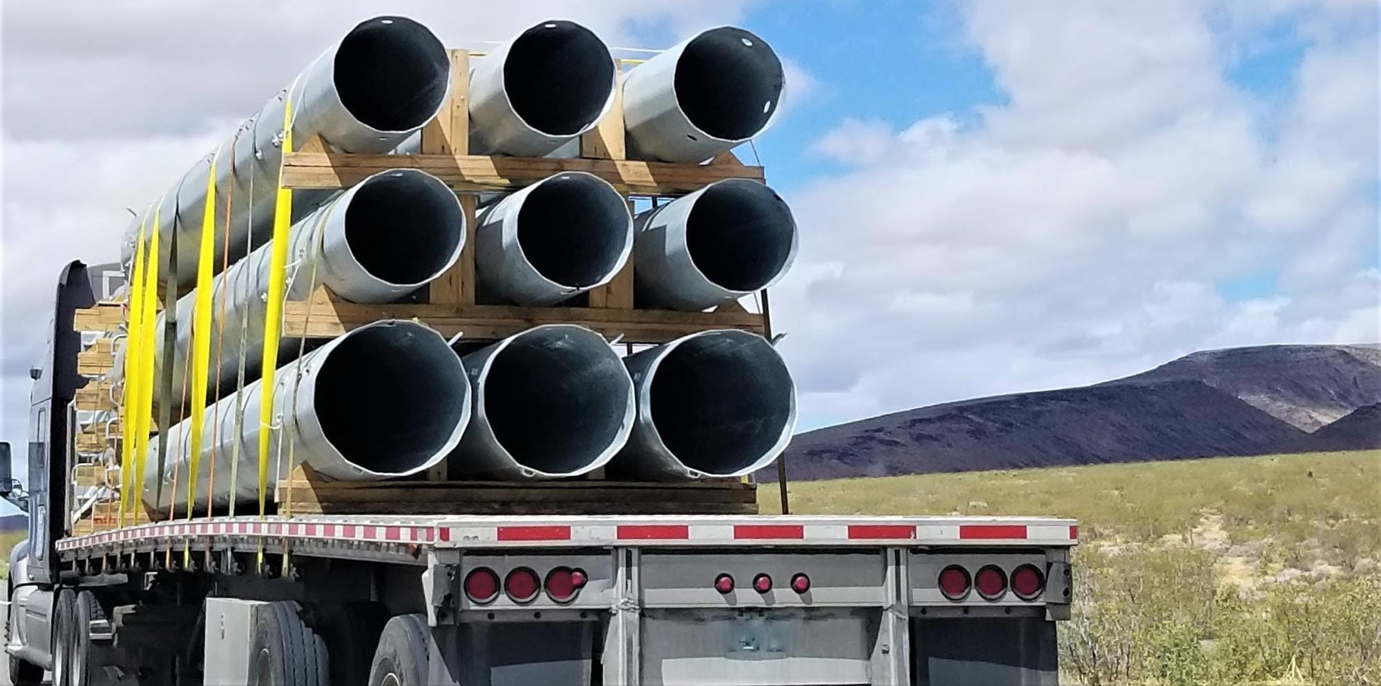 A truck loaded with pipes on the back of it.
