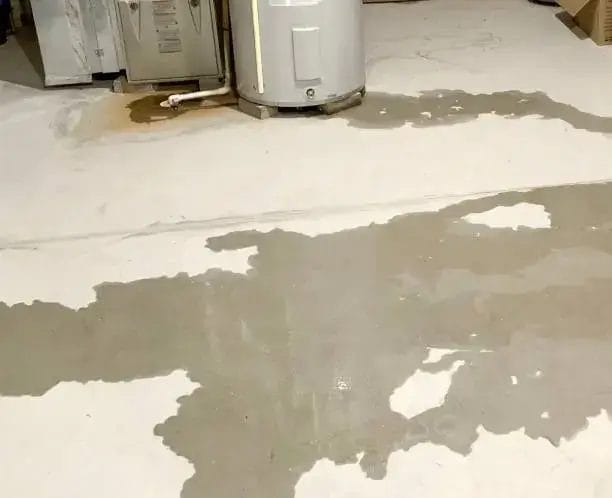 Water leaking from a water heater and furnace onto a concrete basement floor.